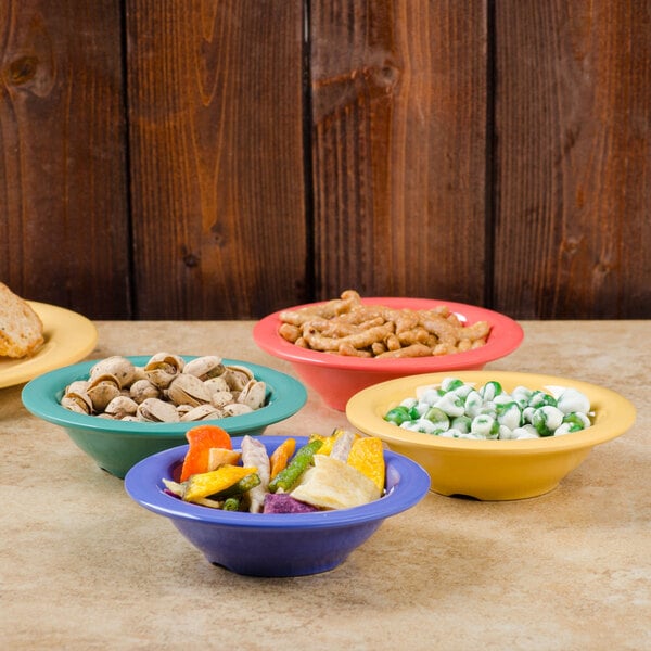 A table with colorful bowls of food including a GET Diamond Mardi Gras melamine bowl.
