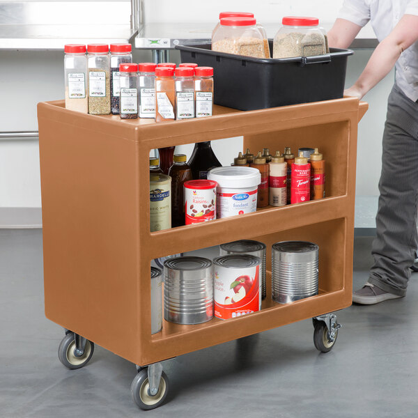 A Cambro beige plastic service cart with three shelves holding clear food containers with red lids.