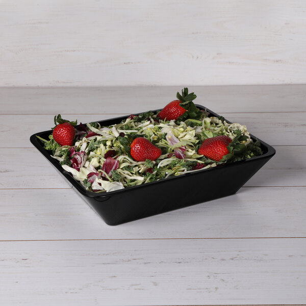 A salad in a black melamine bowl with strawberries.
