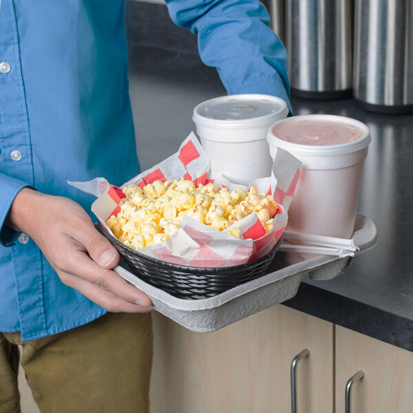 A man holding a Huhtamaki Chinet 2 cup carrier with popcorn and two drinks.