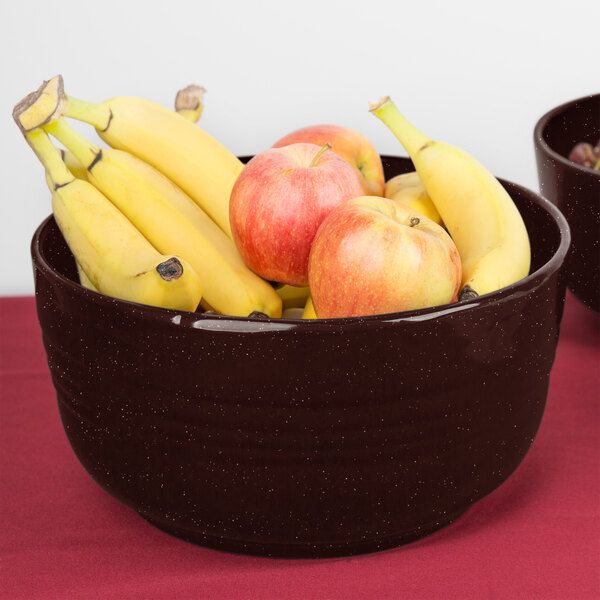 A Tablecraft Midnight Speckle cast aluminum bowl filled with bananas and apples on a table.