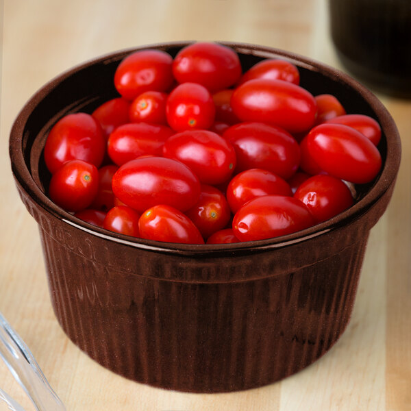 A Tablecraft maroon speckle cast aluminum souffle bowl filled with cherry tomatoes on a counter