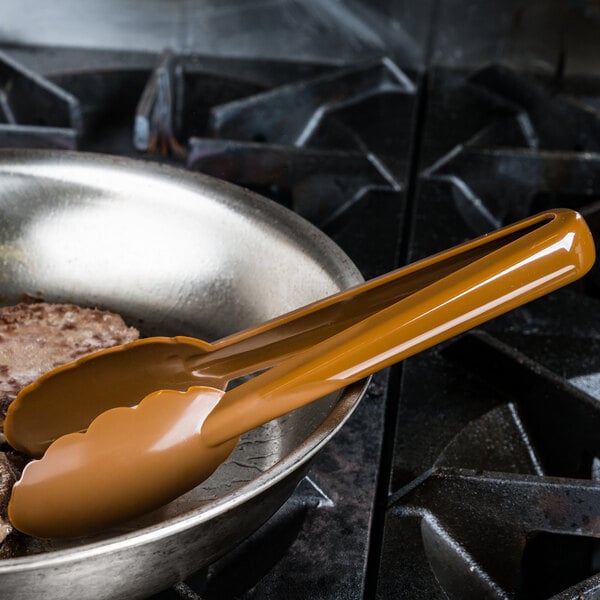 A pan with brown plastic tongs on it.