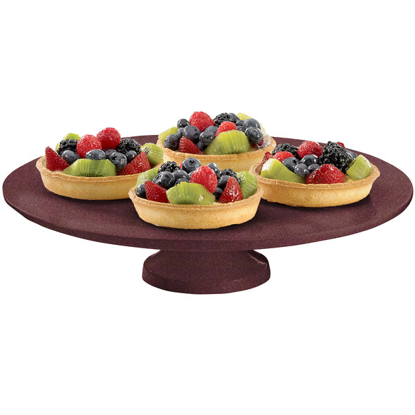 A Tablecraft maroon speckle round platter with fruit on it on a table in a bakery display.
