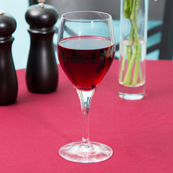 A Chef & Sommelier Exalt wine glass filled with red wine on a table with a red tablecloth.