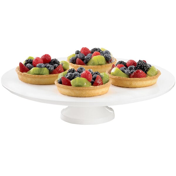 A Tablecraft white cast aluminum round platter with four fruit tarts on it.
