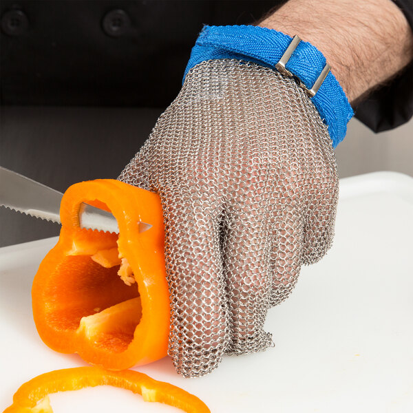 A person wearing a Victorinox blue stainless steel mesh glove cutting a bell pepper.