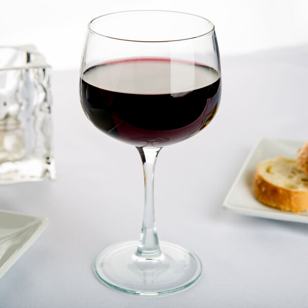 A glass of Arcoroc red wine on a table.