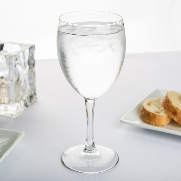 A customizable Arcoroc Grand Savoie wine glass of water on a table next to bread.