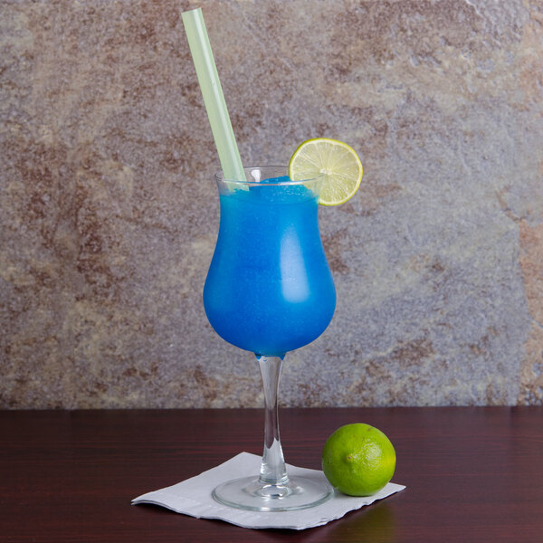 A blue cocktail in an Arcoroc Grand Cuvee glass with a straw and lime slice.