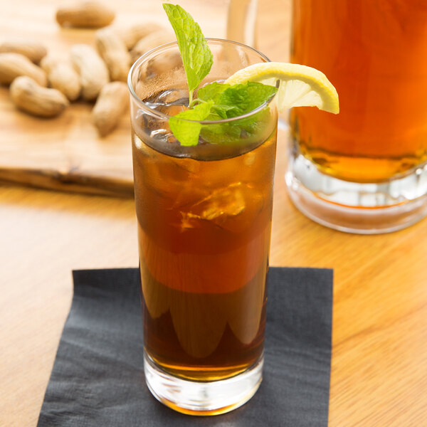 A Libbey tall highball glass of tea with ice, a lemon wedge, and a mint leaf on top.