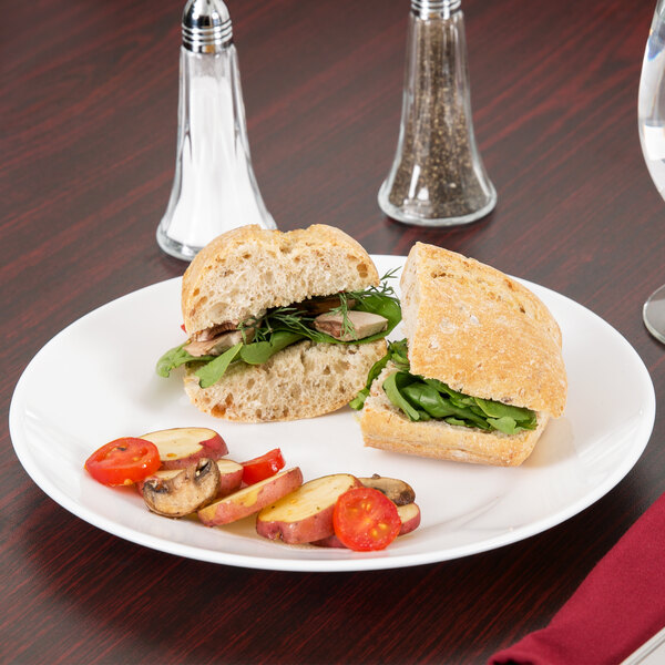 A white Arcoroc glass lunch plate with a sandwich on it.