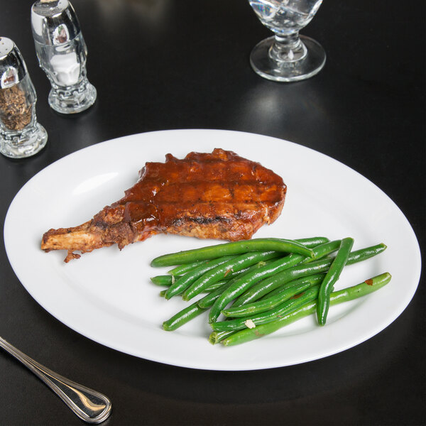 An Arcoroc white oval platter with meat and green beans on it.