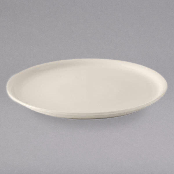 A close-up of a Tuxton eggshell china pizza plate with a rim on a gray surface.