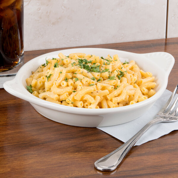 A bowl of macaroni and cheese with a fork on a table.