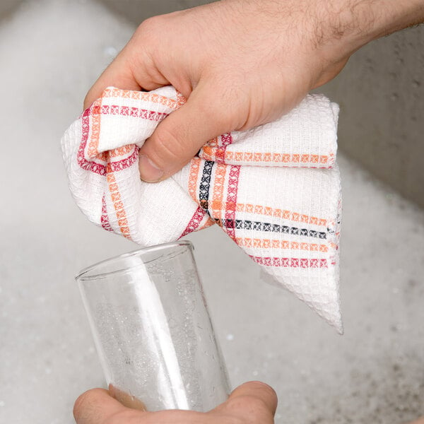 A hand holding a Chef Revival striped waffle-weave dish towel over a glass.