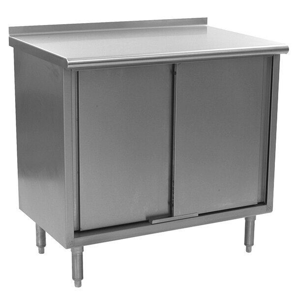 A stainless steel cabinet with a door on a stainless steel work table.