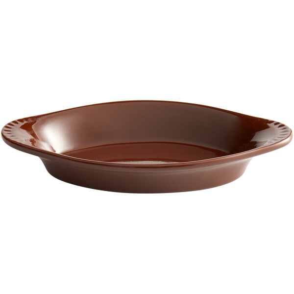 A brown bowl with a handle on an oval white background.