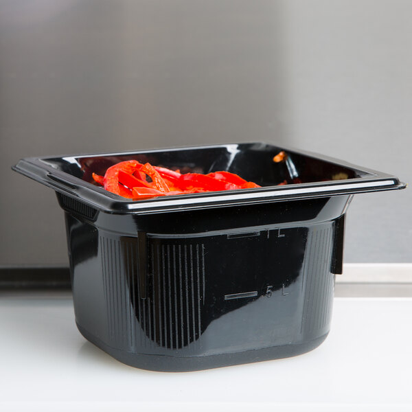 A black Vollrath polycarbonate food pan with red peppers inside.