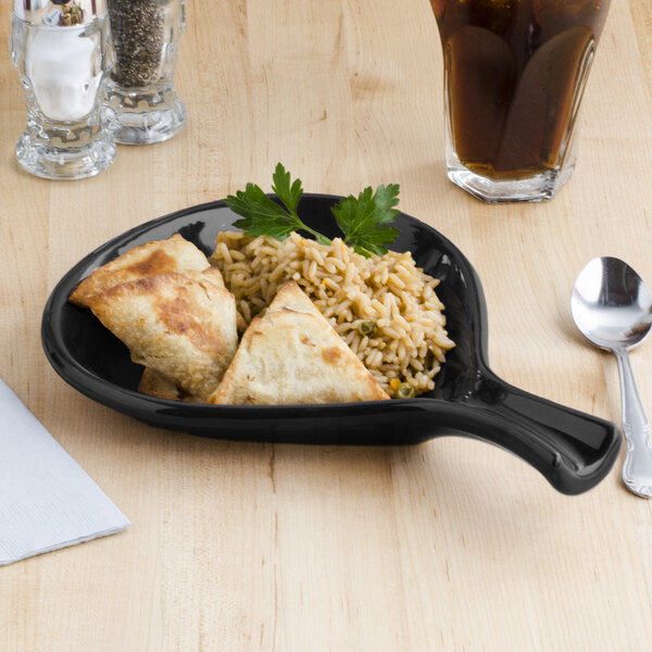 A Tuxton black china fry pan server with food on it on a table.