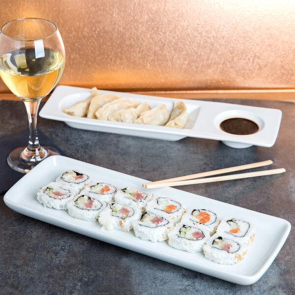 A Tuxton white china tray with sushi and a glass of wine on a table.