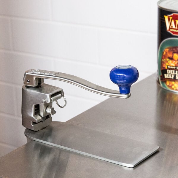 An Edlund heavy duty manual can opener with clamp base on a counter next to a can.