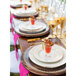 A table set with 10 Strawberry Street gold porcelain luncheon plates and glasses of food.