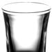 A close-up of a clear Arcoroc shot glass with a black rim.