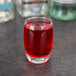 An Arcoroc Salto cordial glass filled with red liquid on a table.