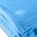A close up of a light blue Oxford polyester fleece blanket with white embroidery.