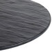 A Tablecraft round melamine display tray with a black faux slate surface.