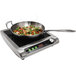 A Vollrath countertop induction range with a pan of vegetables on it.