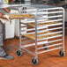 A person placing a tray of cookies on a Cres Cor half height sheet pan rack.