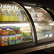 A Vollrath curved refrigerated countertop display case with drinks and beverages inside.