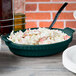 A Tablecraft hunter green shallow oval casserole dish filled with food on a table.