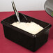 A black Tablecraft rectangle server with white rice and a spoon.