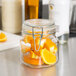 A Libbey glass jar filled with orange slices and a clamp lid on a counter.