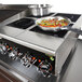 A Vollrath countertop induction hot plate with a pan of food on it.