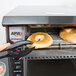 A bagel being cooked in an APW Wyott conveyor toaster.