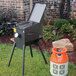 An R & V Works outdoor fryer with legs on a grassy area next to a gas cylinder.