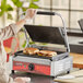 A woman using an Avantco commercial panini grill to cook a sandwich.