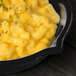A Tablecraft black cast aluminum fry pan filled with macaroni and cheese on a counter.