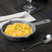 A Tablecraft granite cast aluminum fry pan with macaroni and cheese on a table.