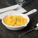 A Tablecraft white cast aluminum fry pan filled with macaroni and cheese on a table with a fork.