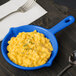 A blue pan with macaroni and cheese in it on a table.