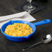 A blue Tablecraft cast aluminum fry pan with macaroni and cheese in it.