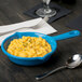 A Tablecraft sky blue fry pan with macaroni and cheese in it.