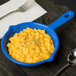A blue Tablecraft fry pan with macaroni and cheese in it.
