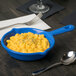 A Tablecraft blue speckle cast aluminum fry pan with macaroni and cheese in it on a table.