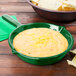 A green Tablecraft fry pan with cheese and tortilla chips.